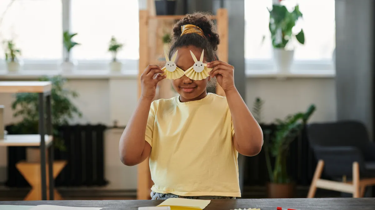 Child holding paper bunny glasses crafts
