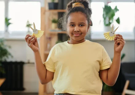 Child holding two paper bunny crafts