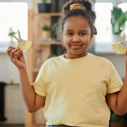 Child holding two paper bunny crafts
