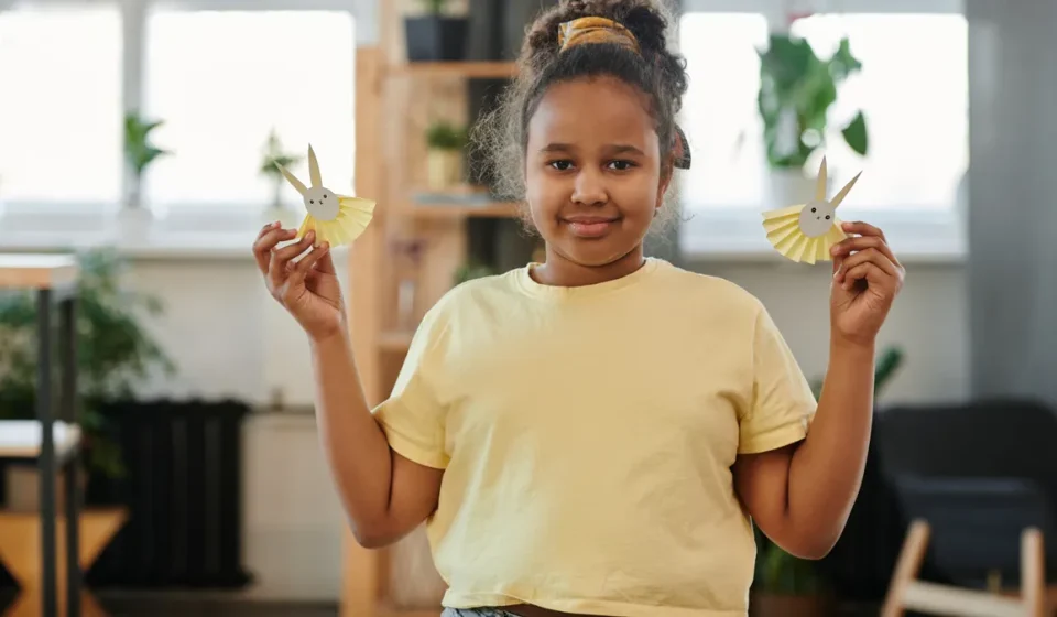 Child holding two paper bunny crafts