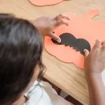 Child making a paper pumpkin craft