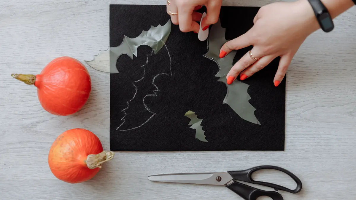 Hands cutting black paper with Halloween shapes