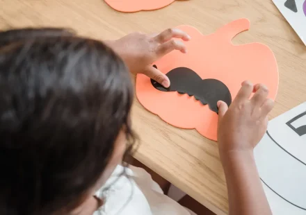 Child making a paper pumpkin craft
