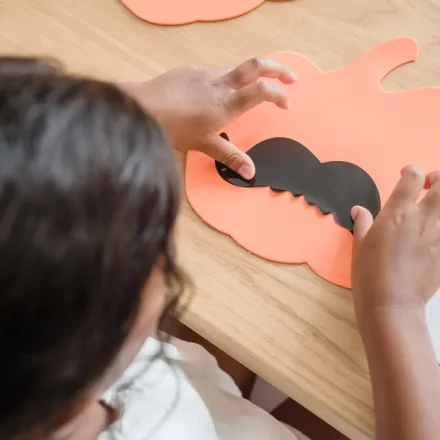 Child making a paper pumpkin craft
