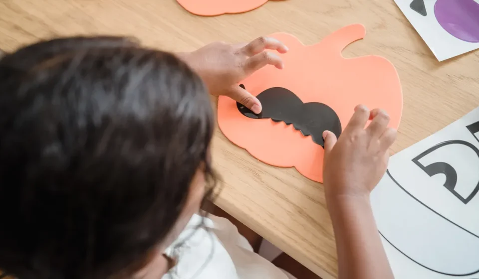 Child making a paper pumpkin craft