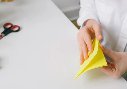 Person folding yellow origami paper at a desk