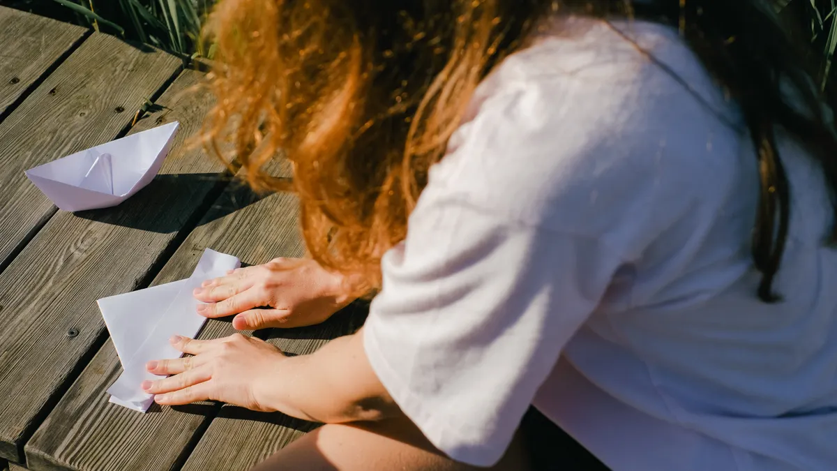 Person folding white paper outdoors
