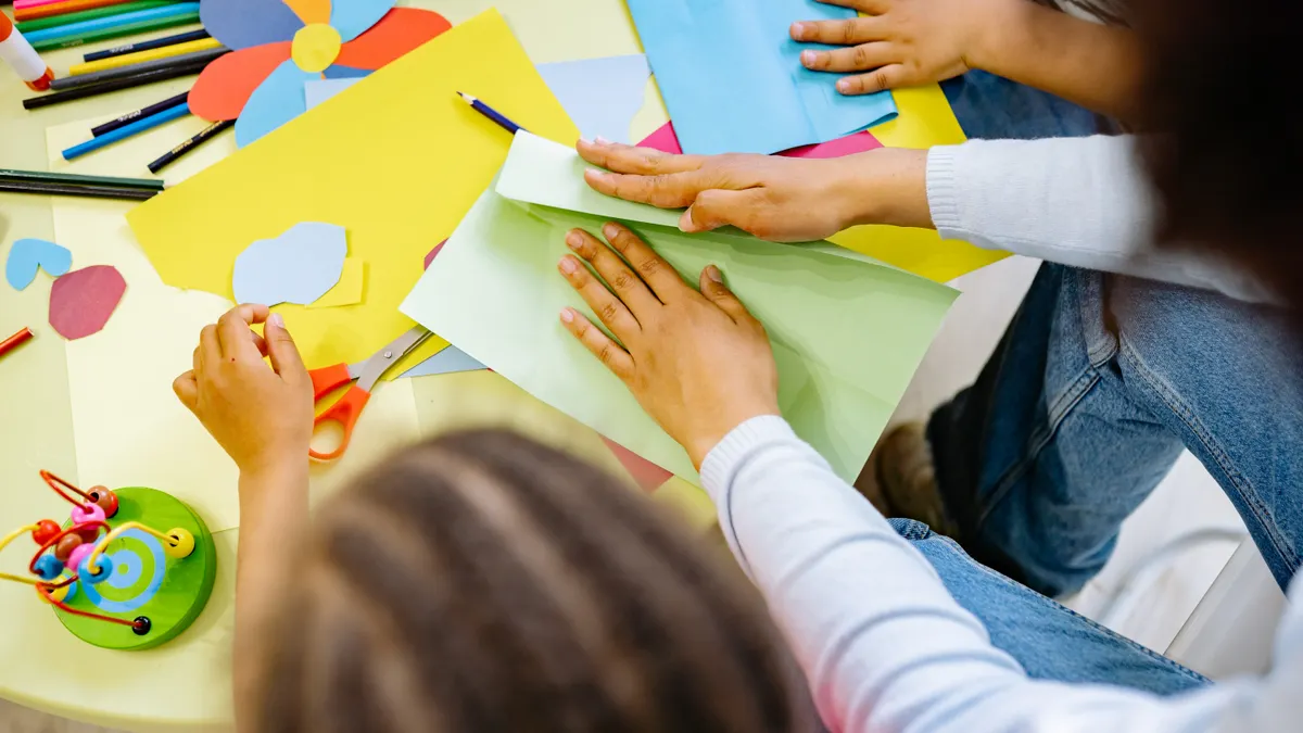 Hands and children working with colored paper and scissors